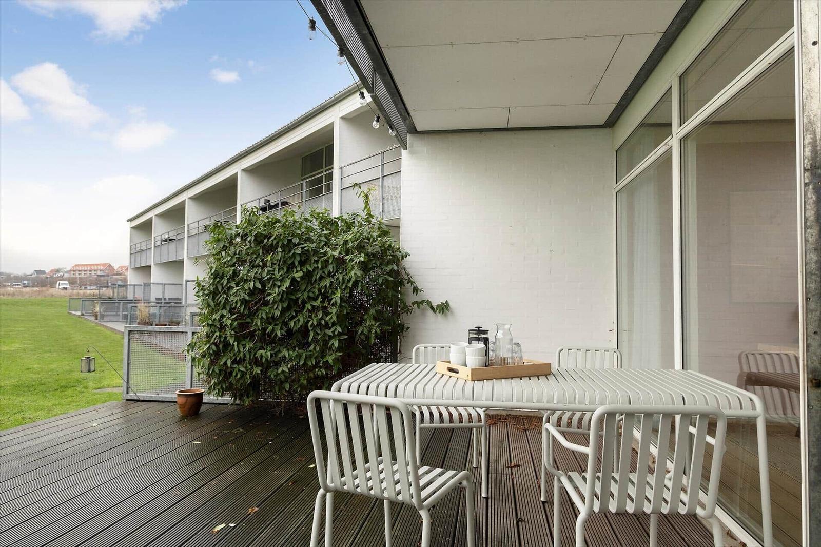 Terrace with table and chairs, view of green area and building