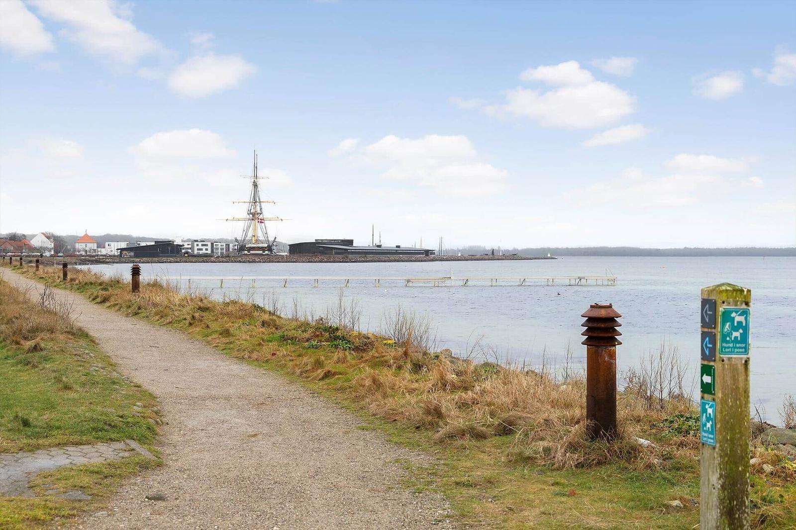 Path by the water with view of a ship and dog signs.