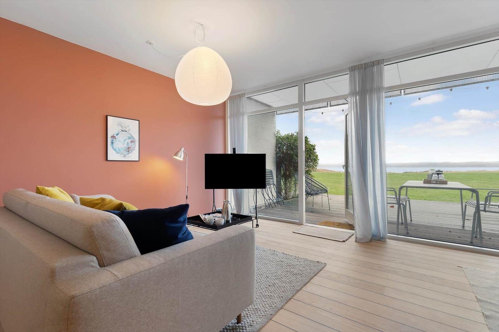 Living room with sofa, TV, and view of terrace and green area.