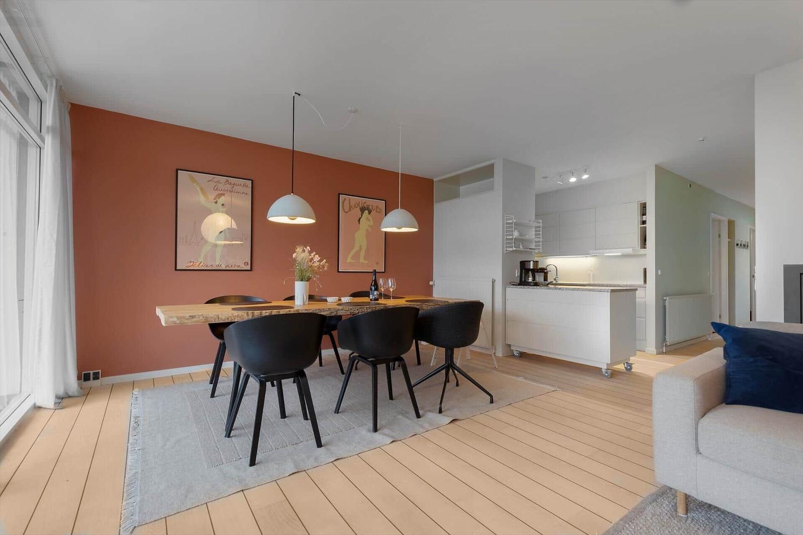 Dining area with table, chairs, and wall posters. Kitchen with countertop and cabinets.