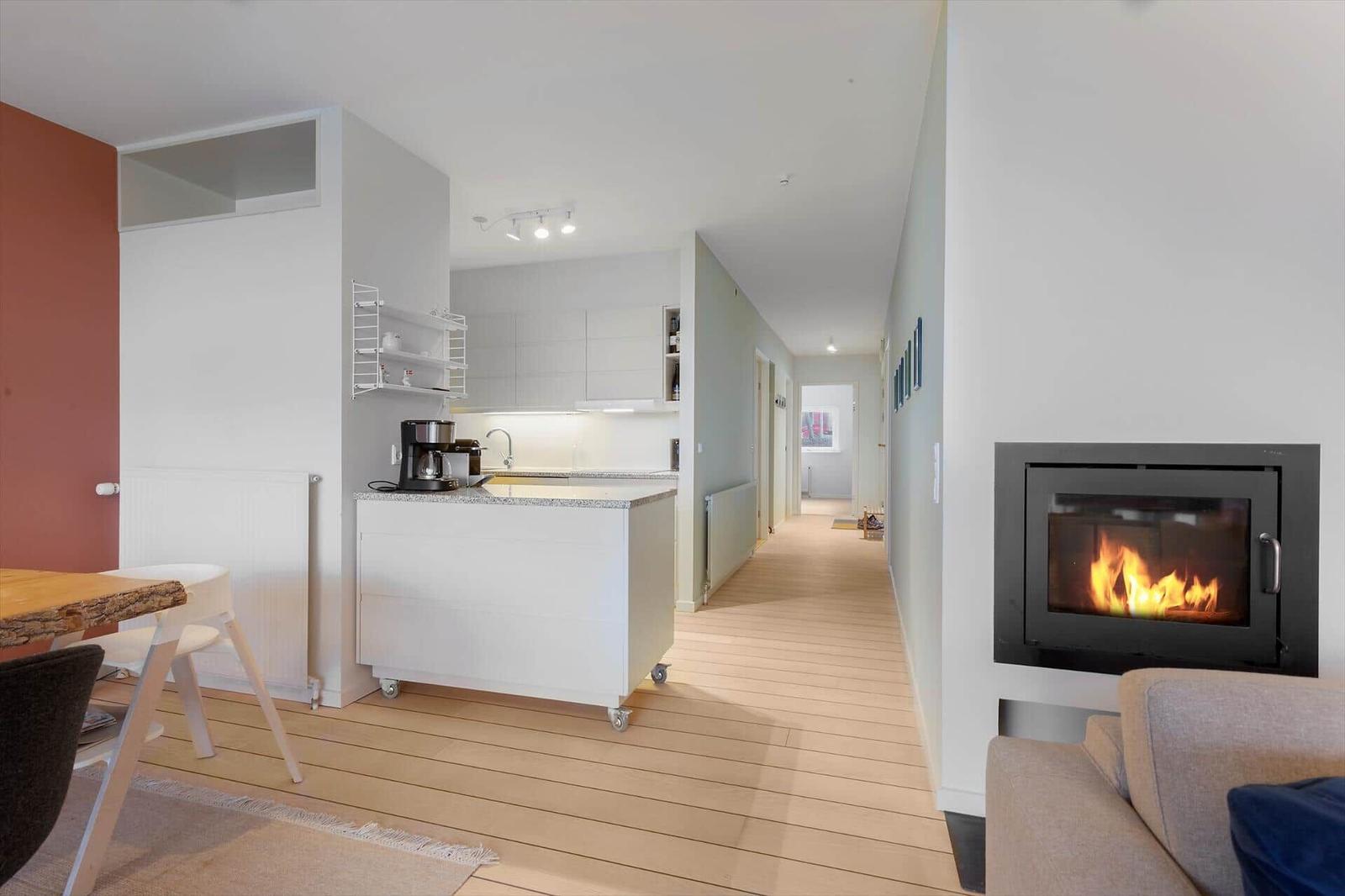 Living area with fireplace, kitchen, and dining area with wooden floor and modern furnishings.