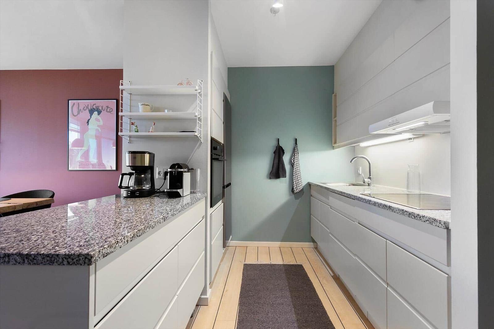 Kitchen with countertop, sink, and appliances. Wall colors pink and green.