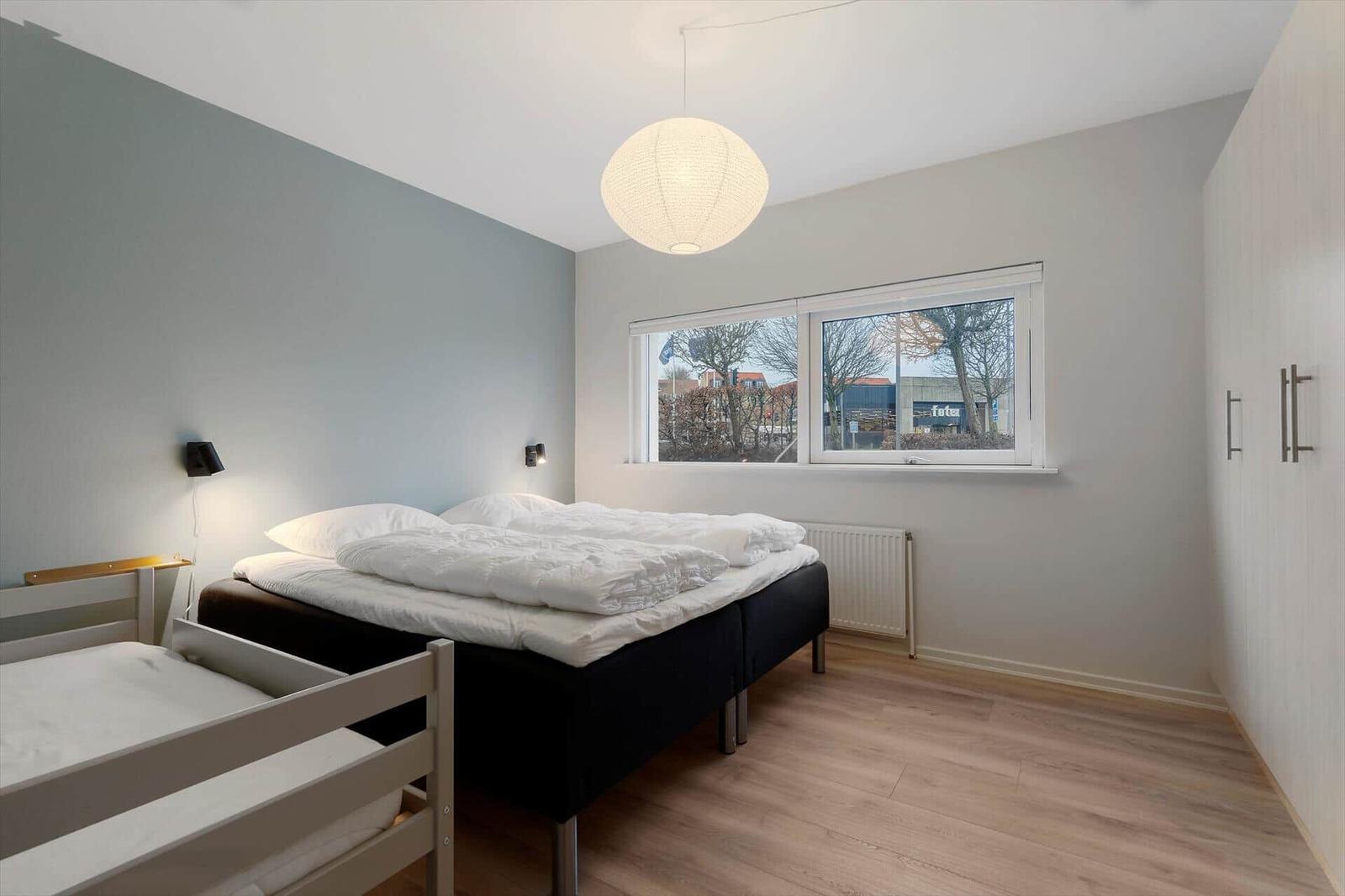 Bedroom with double bed, child bed, window, and wardrobe.