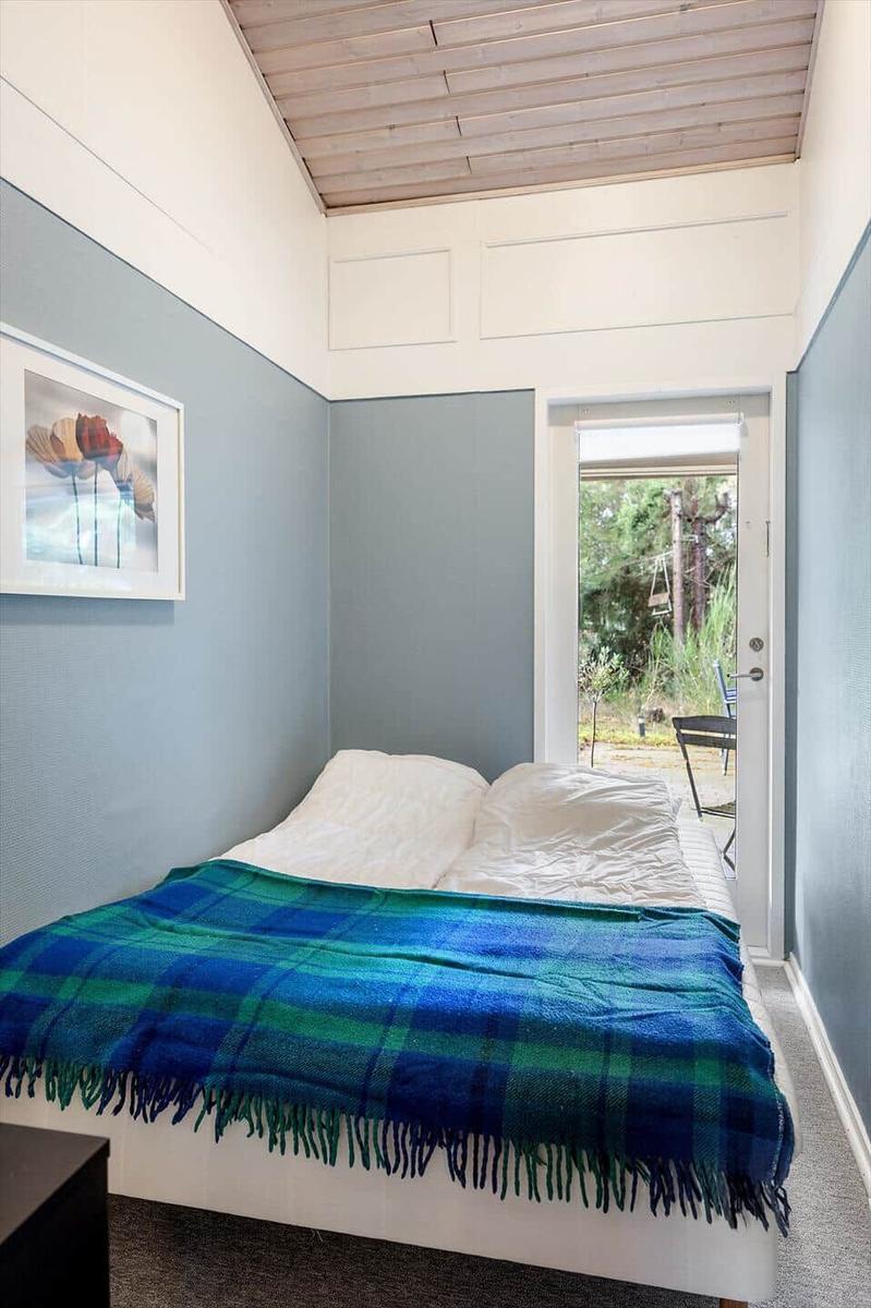 Bedroom with bed, blanket, and door to outdoor area.