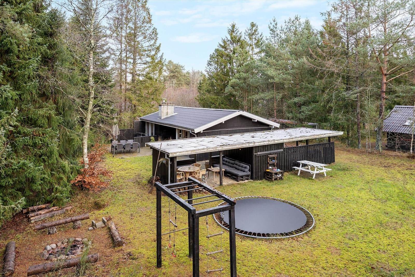 House with terrace, trampoline, and play area in the forest.
