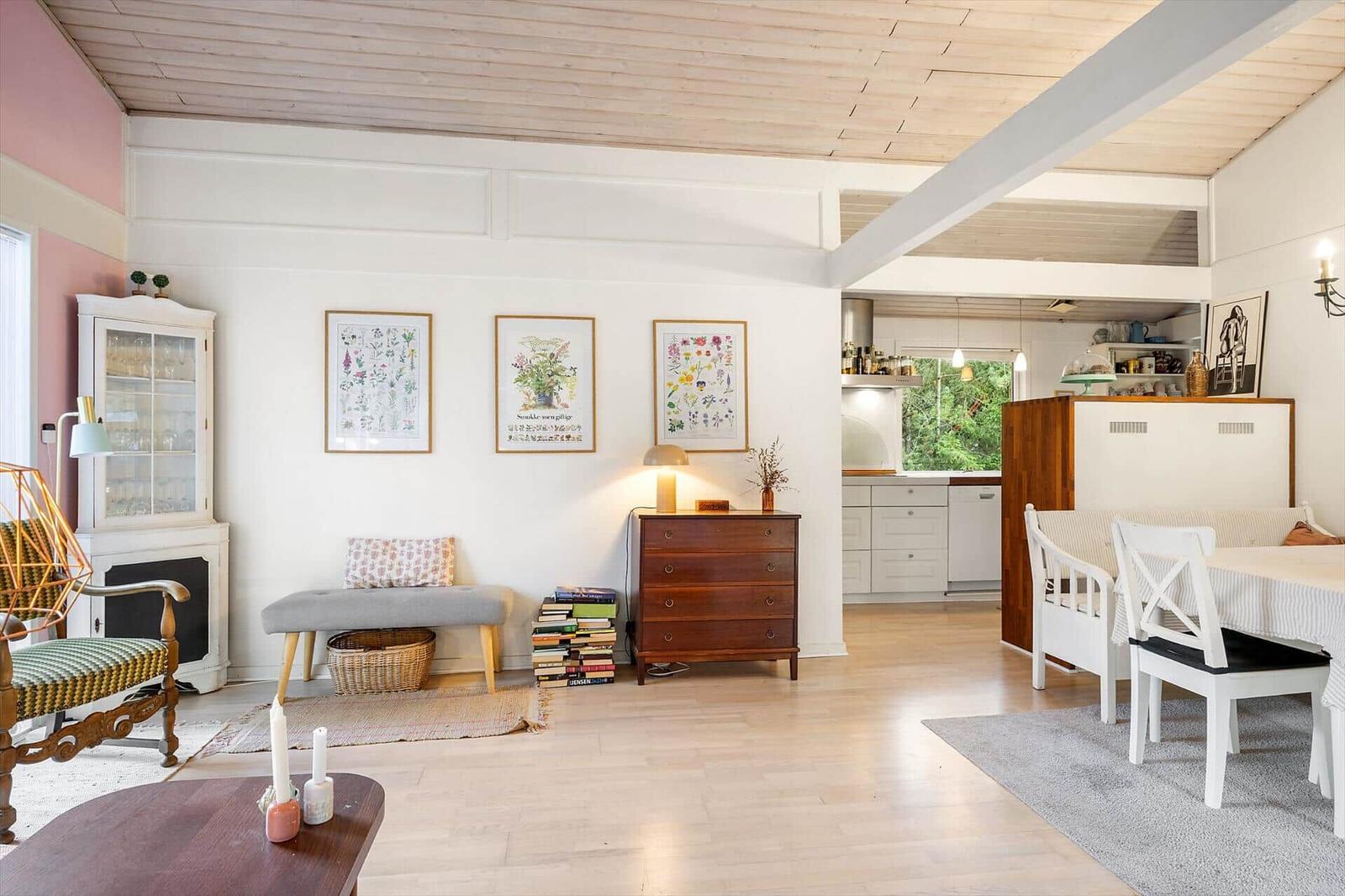 Living and dining area with wooden floor, white walls, and kitchen area in background.