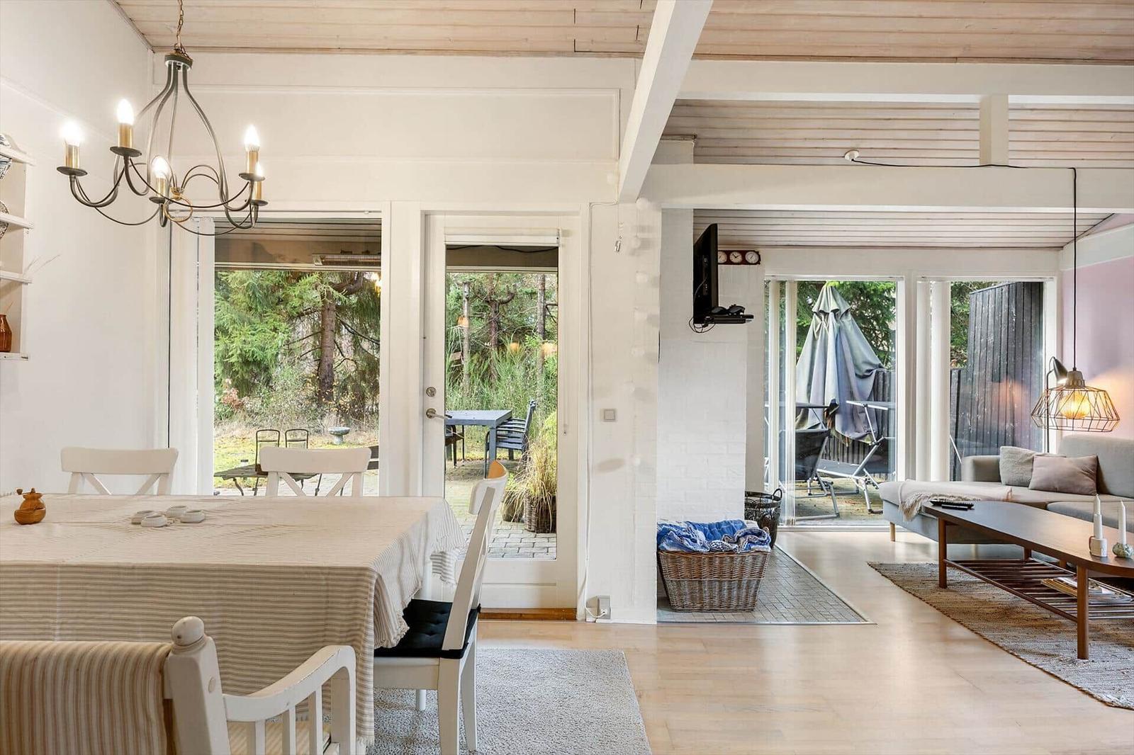 Dining area with table and chairs, living area with sofa and coffee table, view of garden and terrace.
