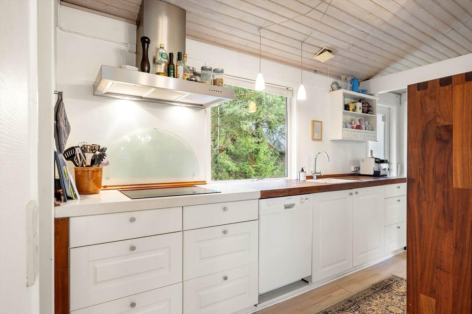 Kitchen with white countertop, wooden surface, and window to the garden.