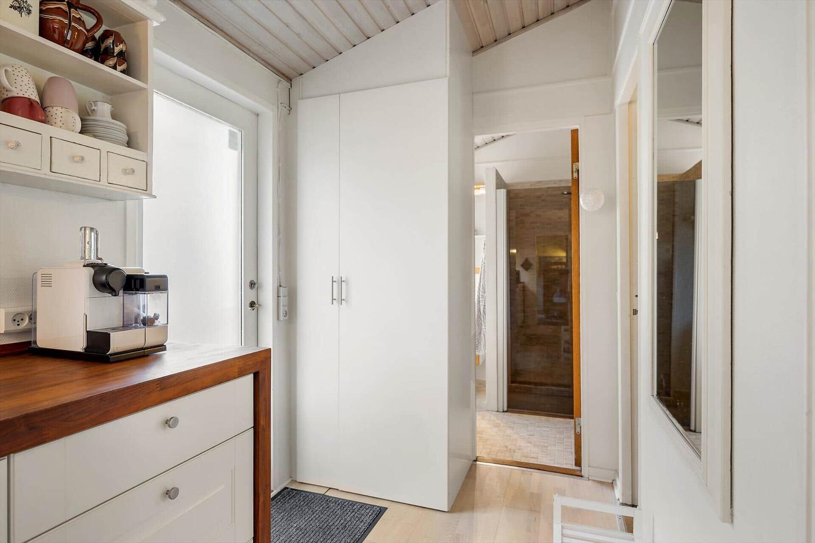 Kitchen with coffee machine, cabinet, and view into the bathroom.