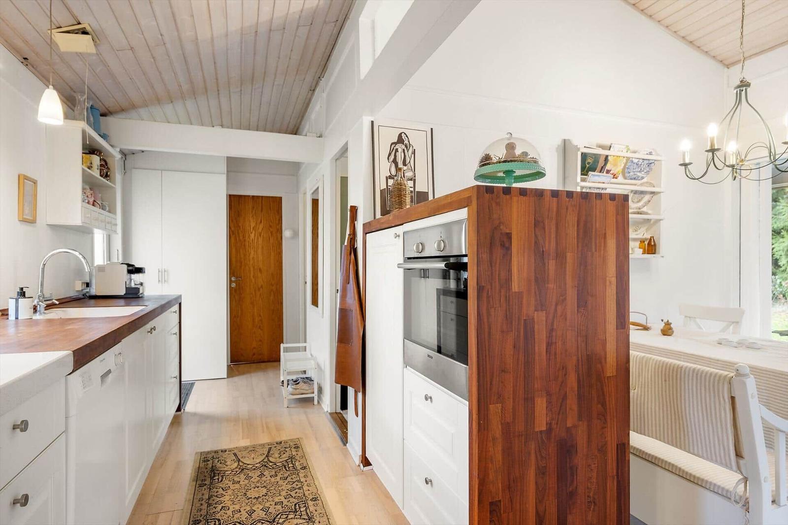 Kitchen with wooden countertop and built-in oven. Dining area with table and chairs.