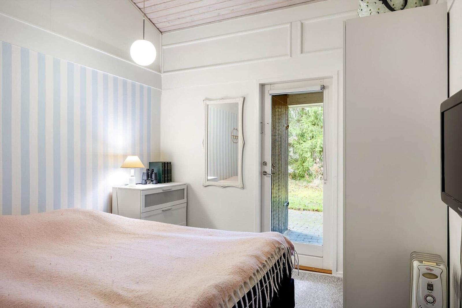 Bedroom with bed, nightstand, mirror, and door to the garden.