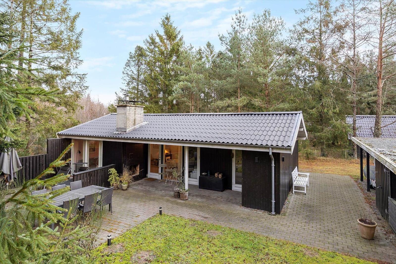 A house with terrace, grill and garden surrounded by trees.