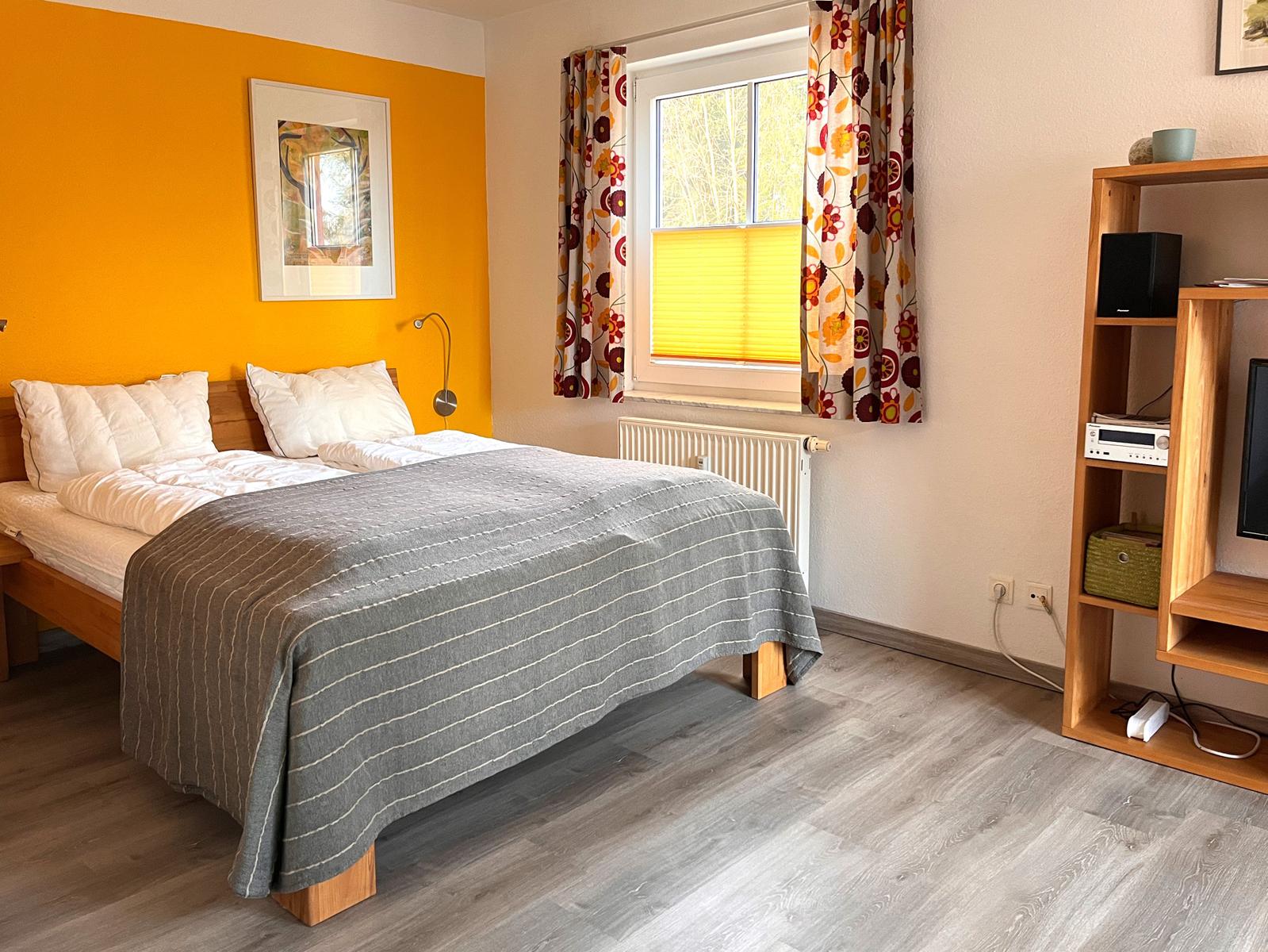 Schlafzimmer mit Bett, Fenster und Holzmöbel.