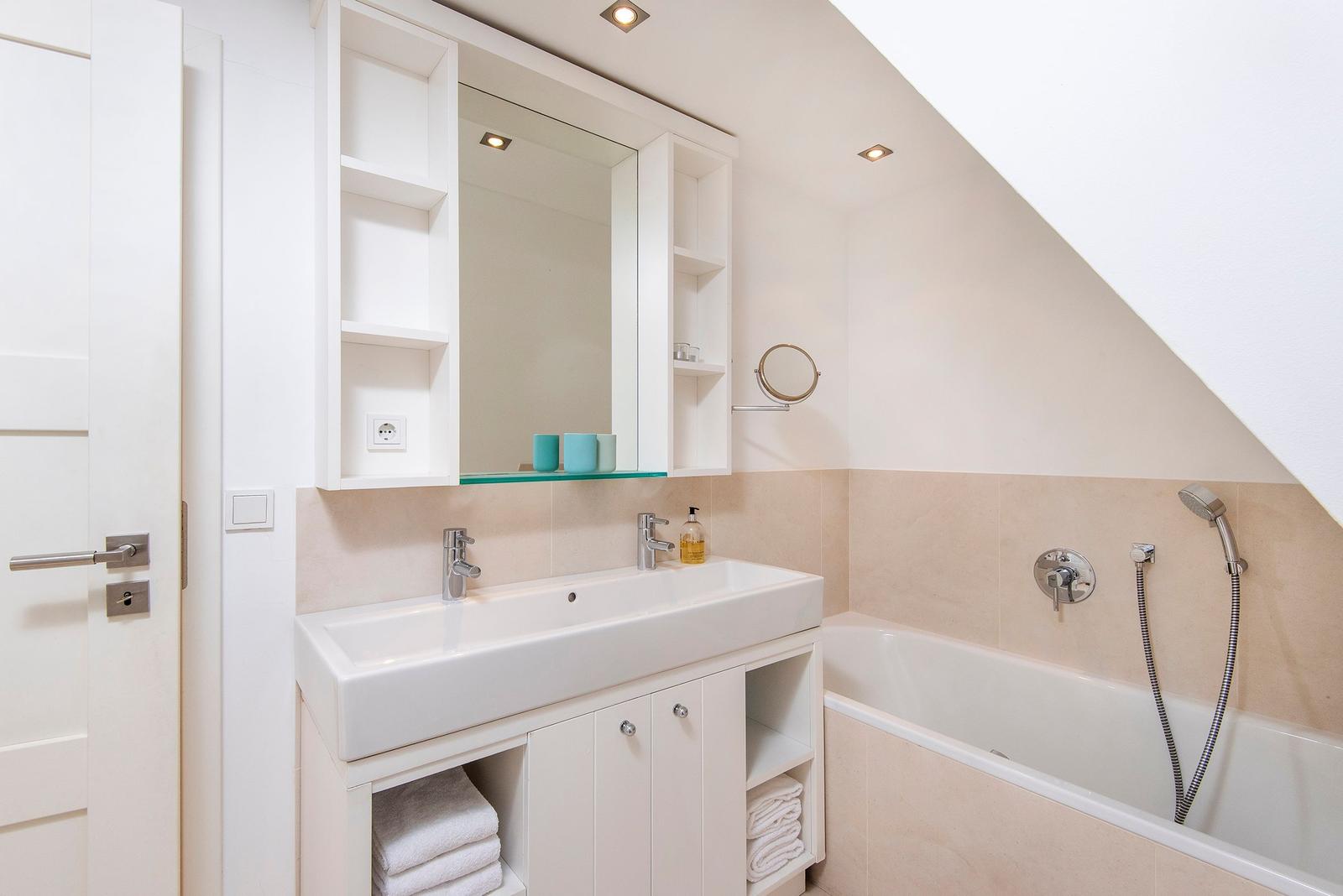 Badezimmer mit Badewanne, Waschbecken und Spiegelschrank.