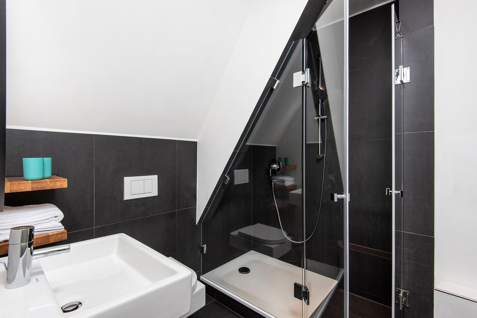 Dusche mit Glaswand, Waschbecken und Toilette in modernem Badezimmer.