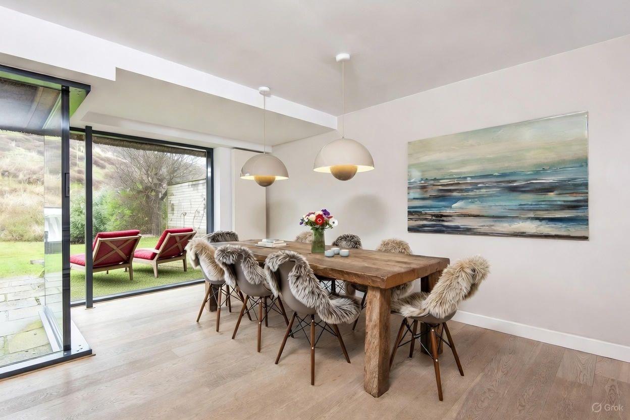 Essbereich mit Holztisch, Stühlen mit Fell und Glasfront zum Garten.