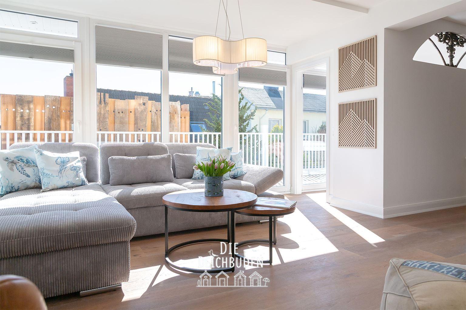 Wohnzimmer mit Sofa, Tisch und Fenstern zur Terrasse.