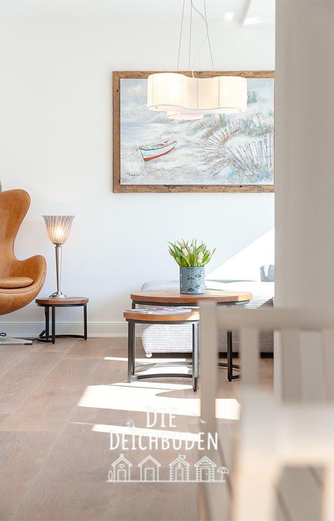 Wohnzimmer mit brauner Sitzgelegenheit, Holztisch und Wandbild mit Boot.