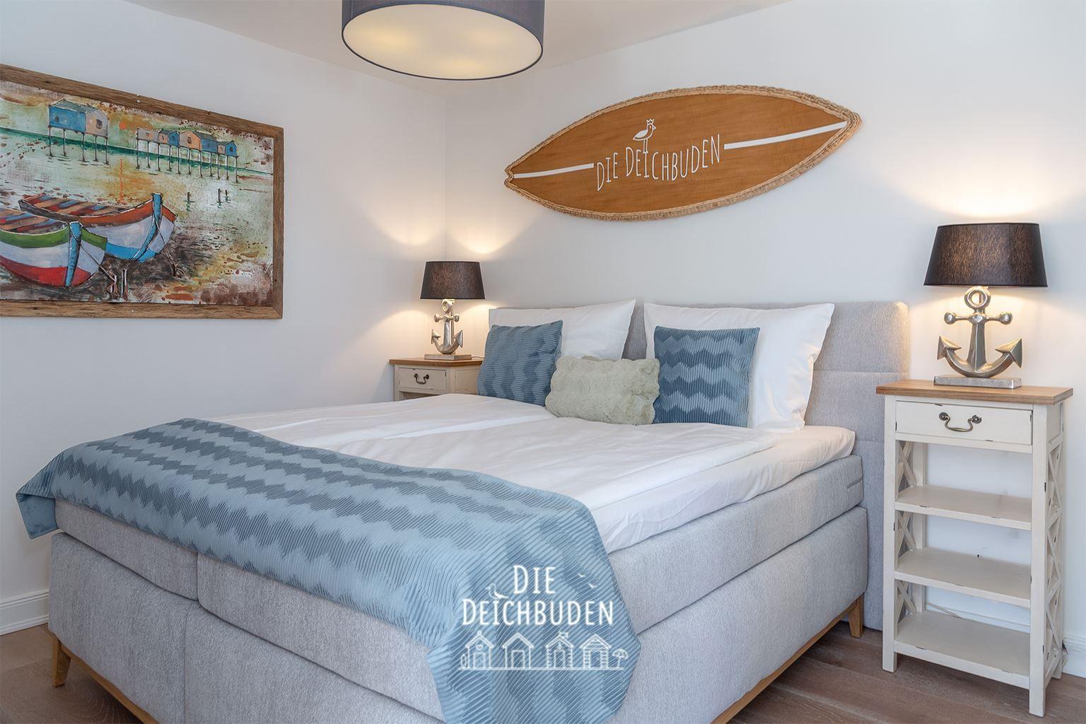 Schlafzimmer mit Bett, Nachttischen und Wanddekoration.