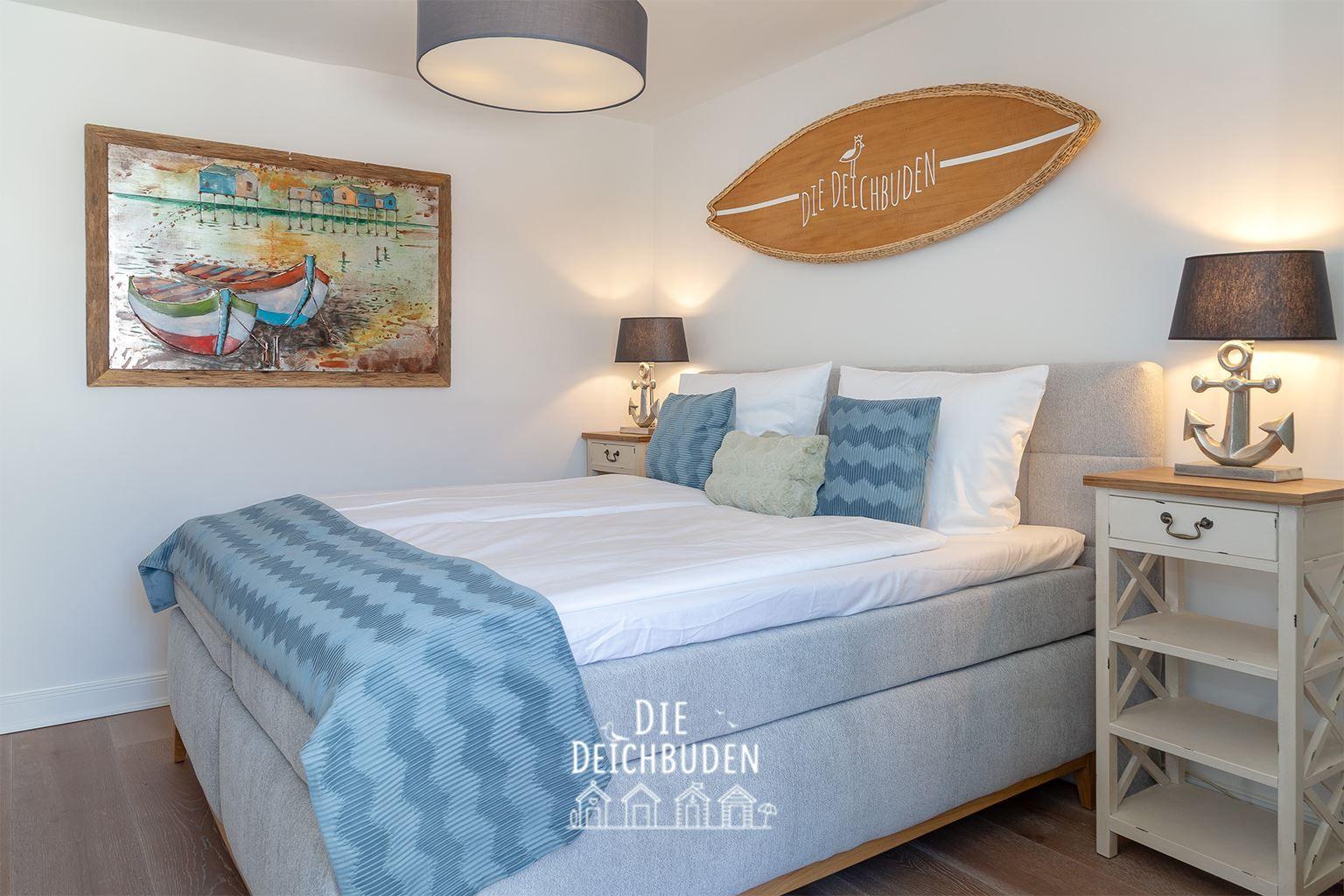 Schlafzimmer mit Bett, Nachttisch und Wanddekoration.