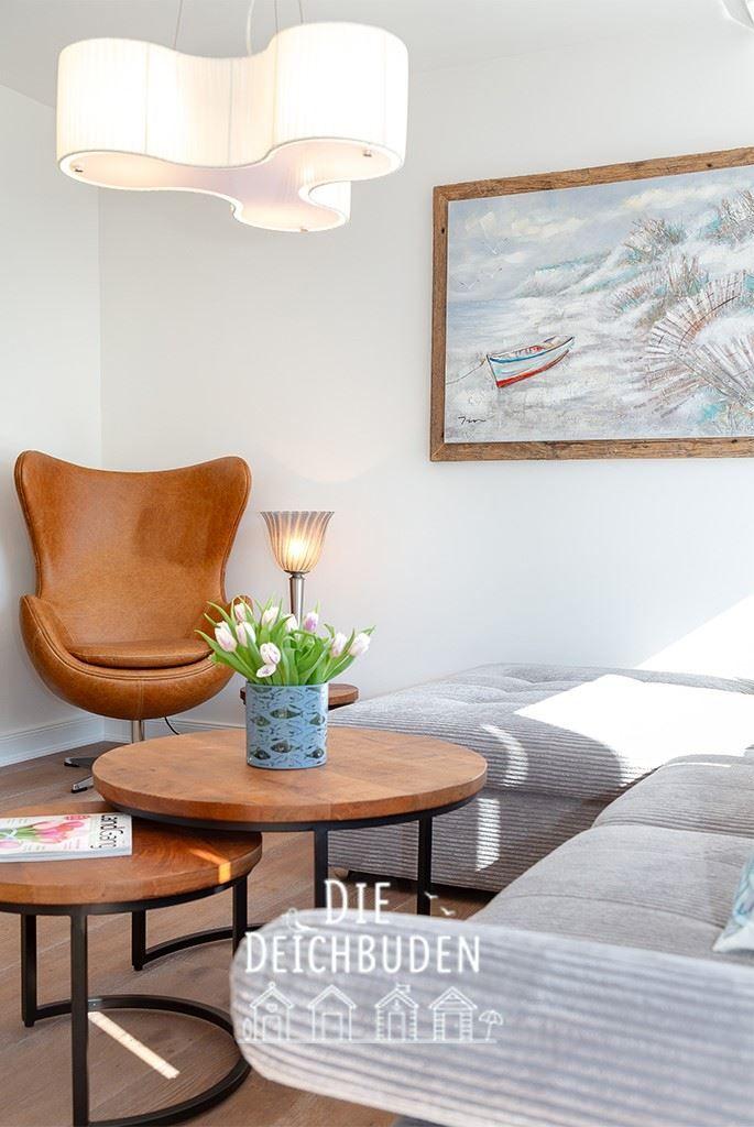 Ein Wohnzimmer mit brauner Ledersessel, Holztisch und Wandbild.