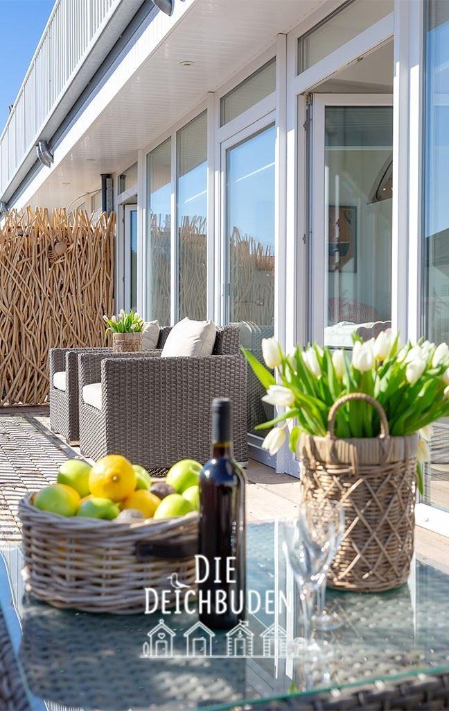 Terrasse mit Sitzgruppe, Blumen und Obsttablett.