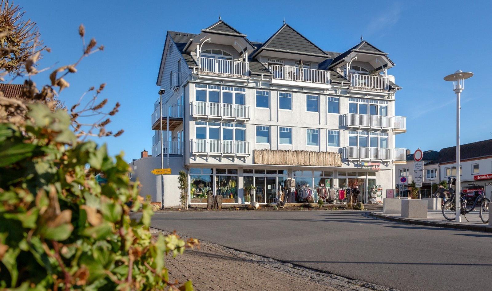 Fünfgeschossiges Haus mit Balkonen und Geschäft im Erdgeschoss.