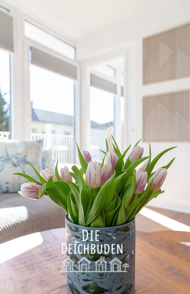 Tulpen in Vase auf Tisch vor Fenster mit Blick auf Balkon.