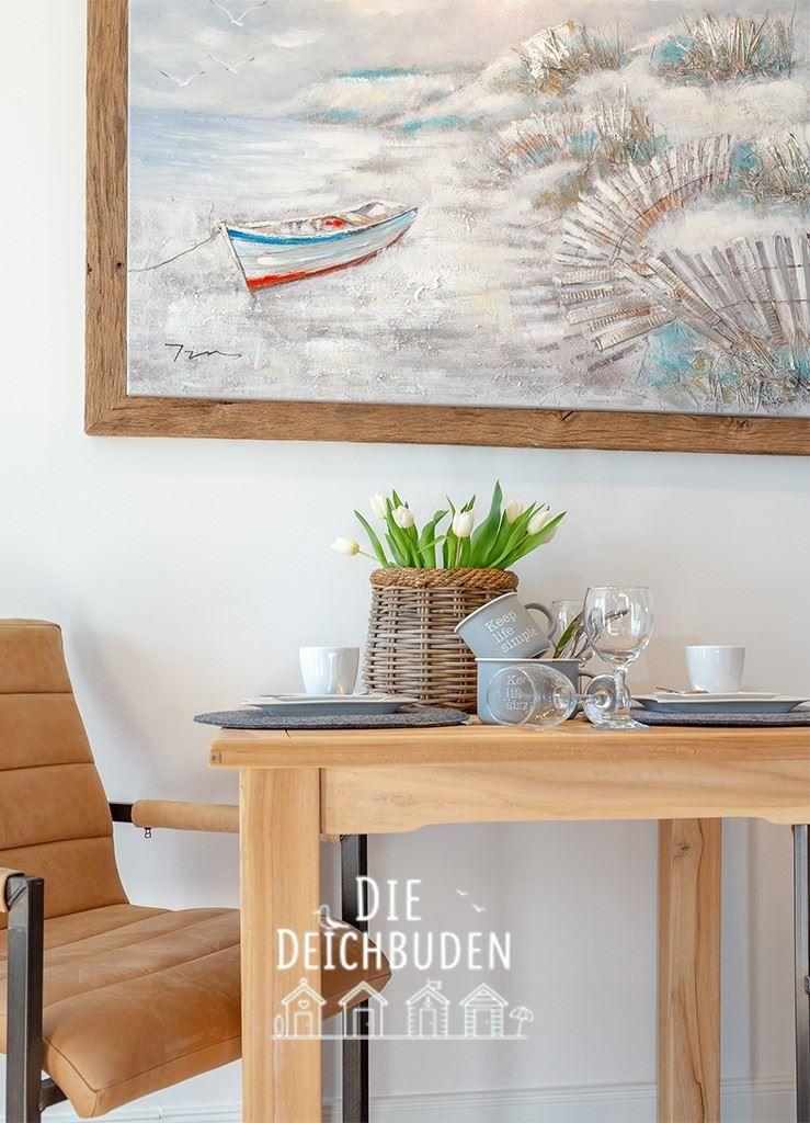 Holztisch mit Stuhl, Blumen und Wandbild mit Boot.