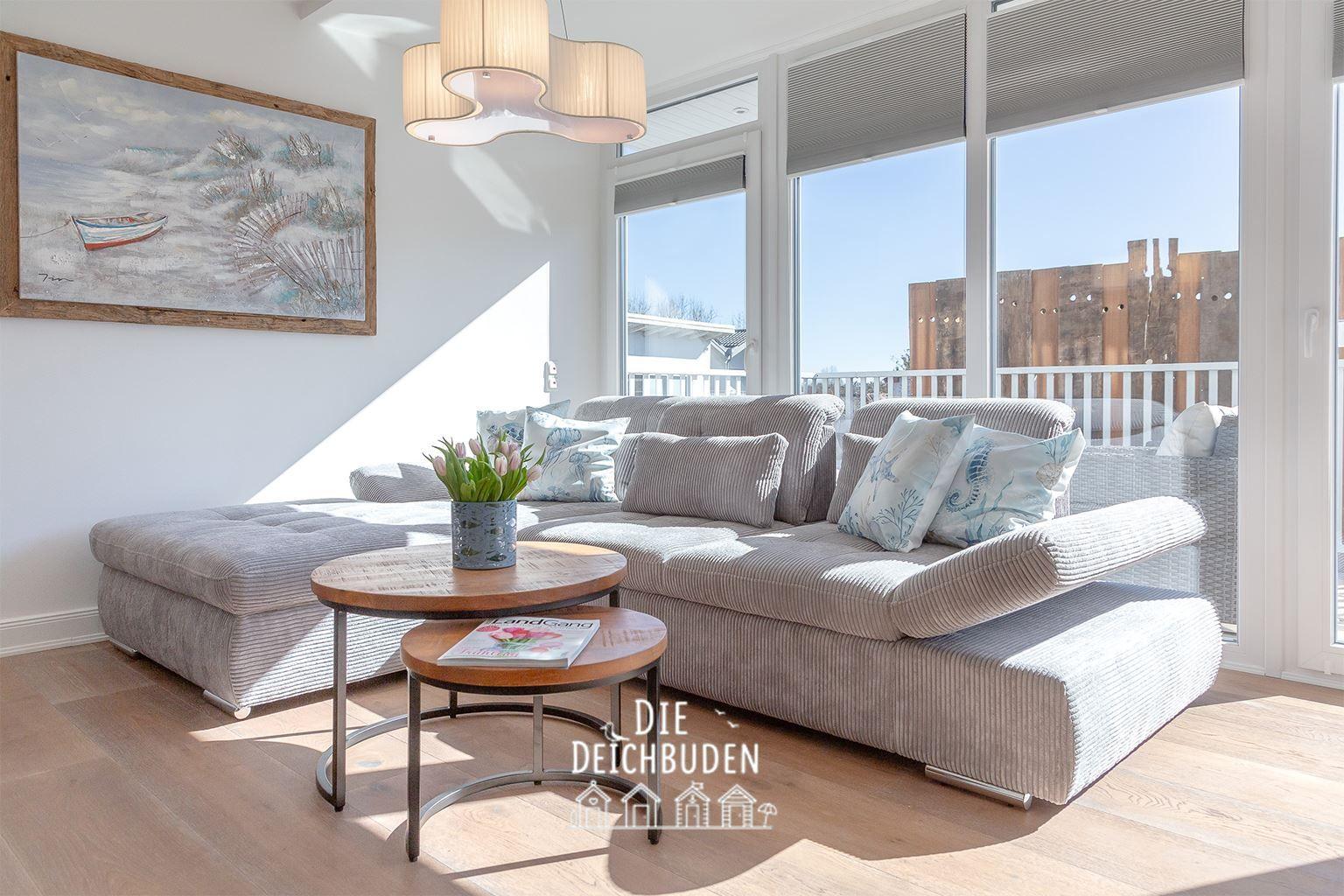 Wohnzimmer mit Sofa, Tisch und Blick auf Balkon.