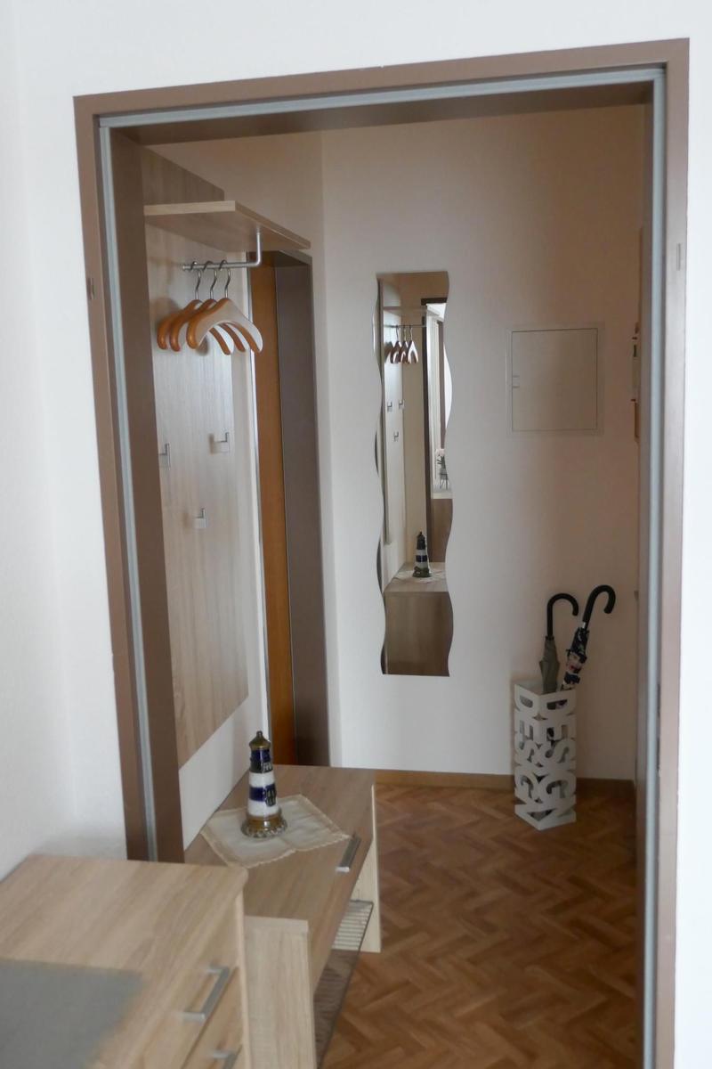 Flur mit Kleiderschrank, Spiegel und Regenschirmständer auf Parkettboden.