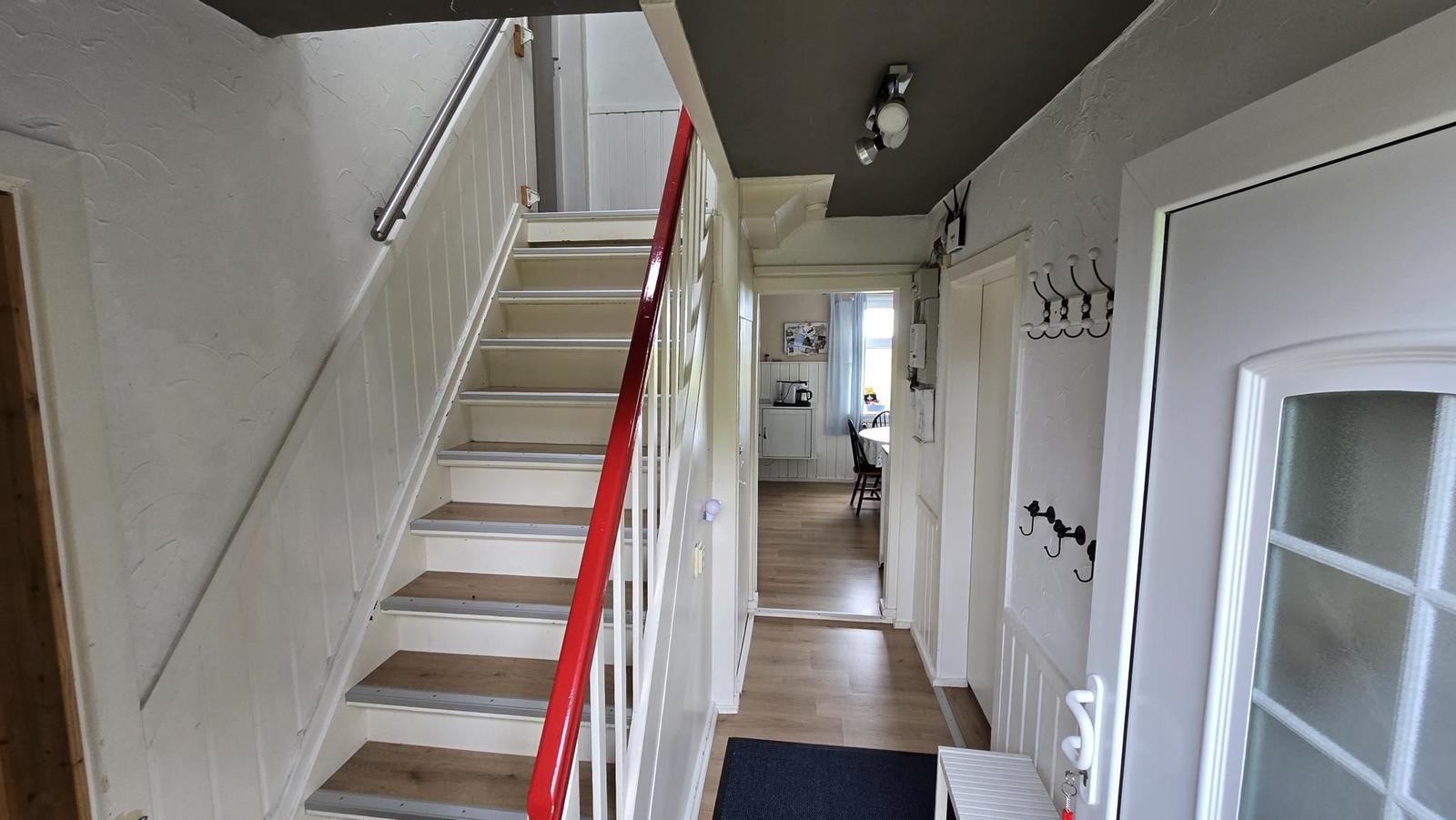 Eingangsbereich mit Treppe, Garderobe und Blick in die Küche.