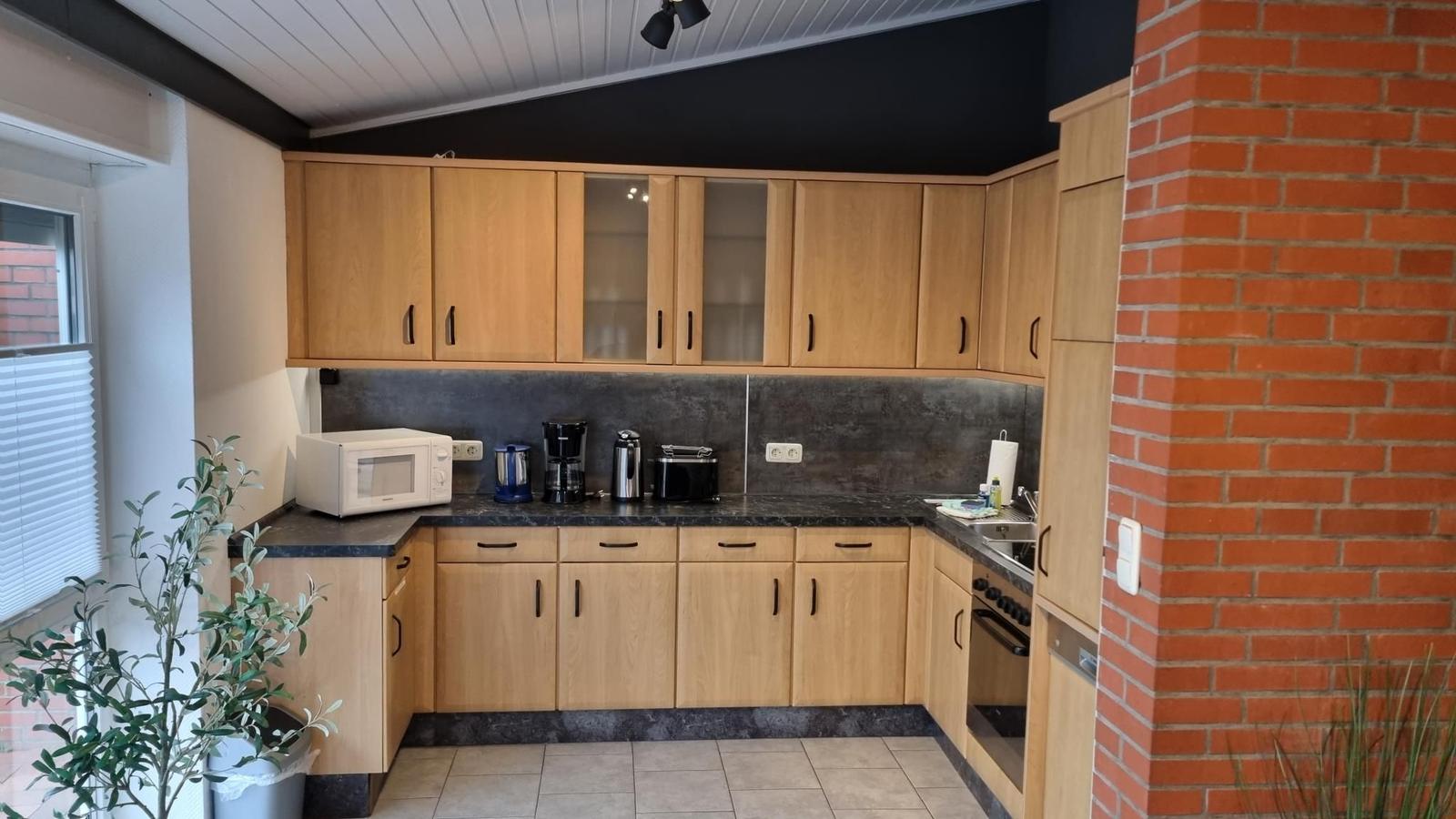 Küche mit Holzschränken, Steinrückwand und rotem Backsteinwand.