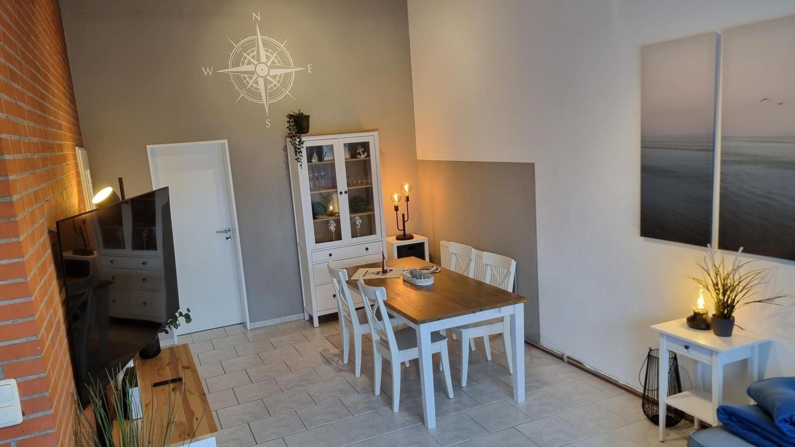 Esszimmer mit Tisch, Stühlen und Glasvitrine an der Wand.