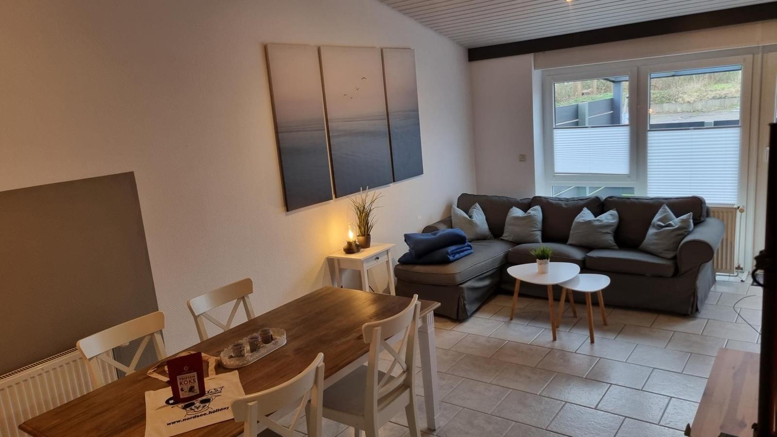 Wohn- und Essbereich mit Sofa, Tisch und Wandbildern.