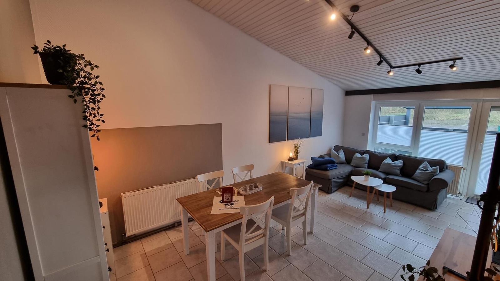 Wohn- und Essbereich mit Sofa, Tisch und Fenster.