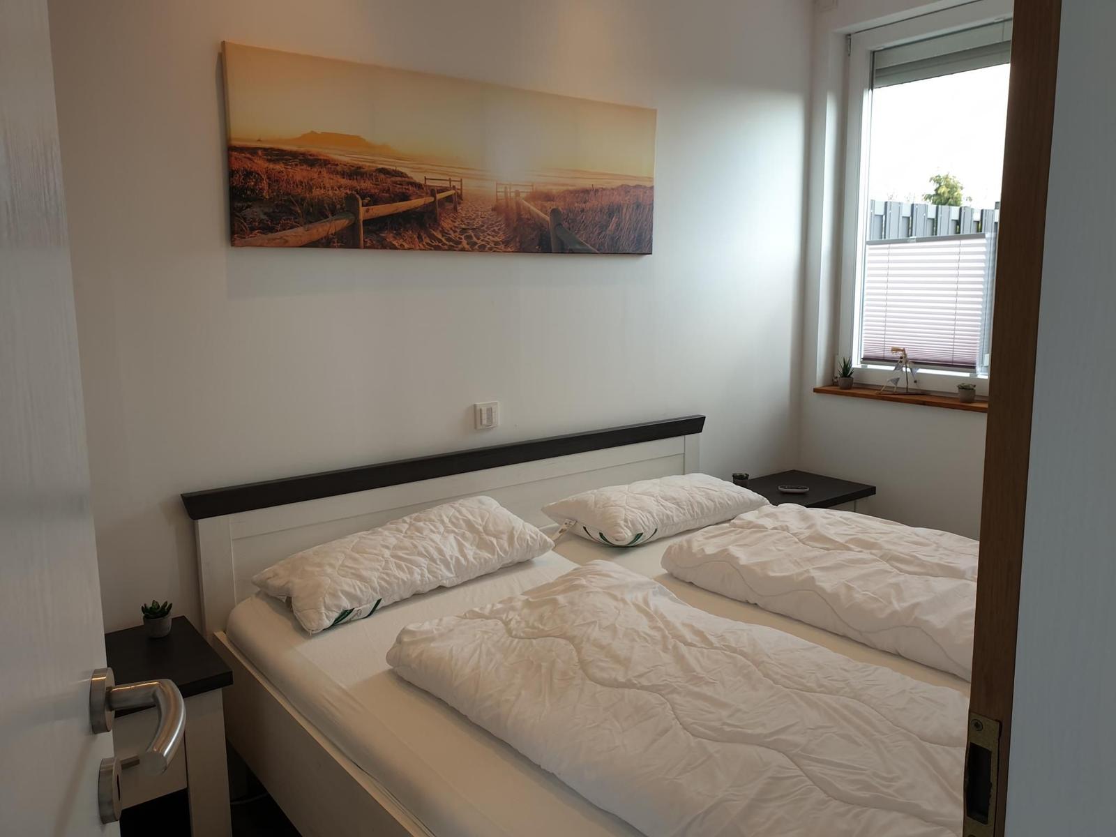 Zwei Betten mit weißen Bettwäsche, Wandbild und Fenster mit Jalousie.