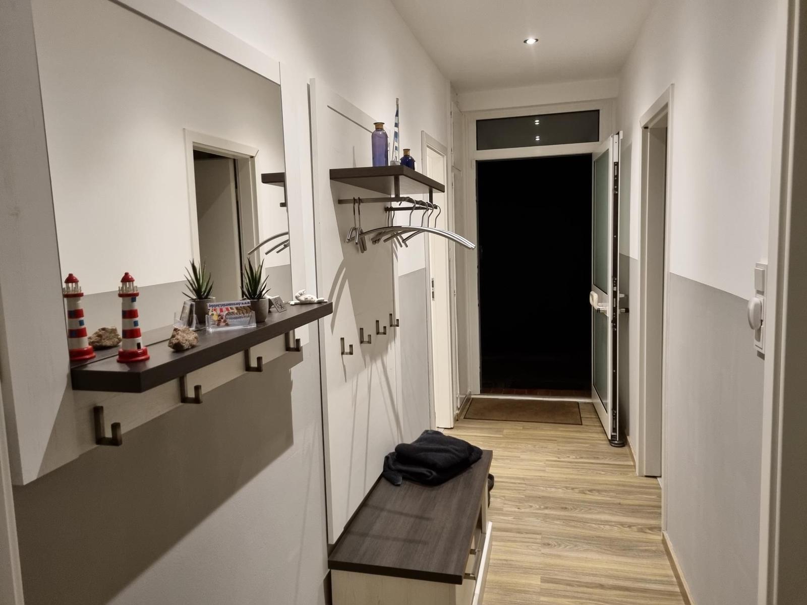 Flur mit Spiegelschrank, Kleiderständer und Holzboden.