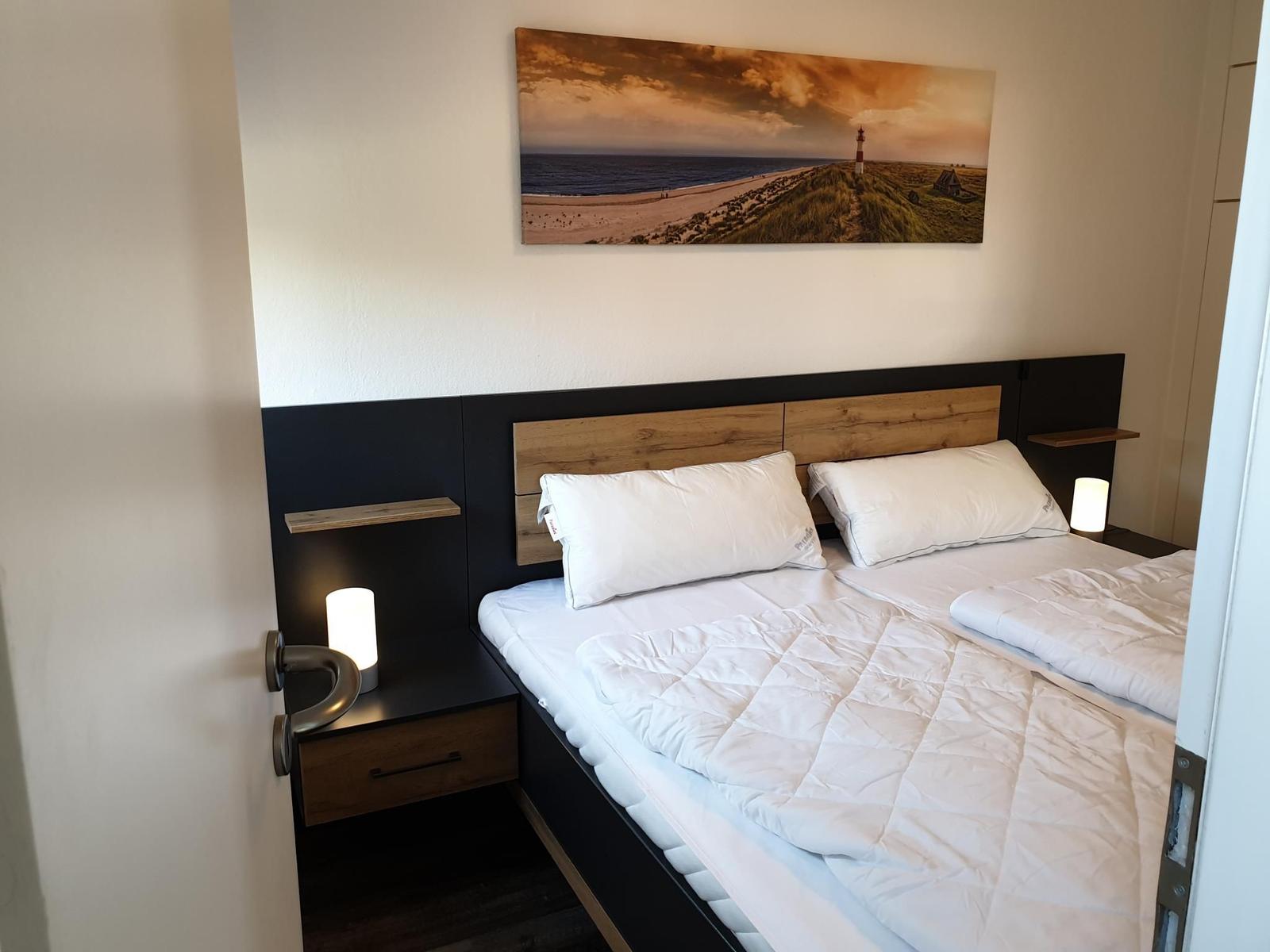 Bedroom with double bed, nightstands, and wall art.