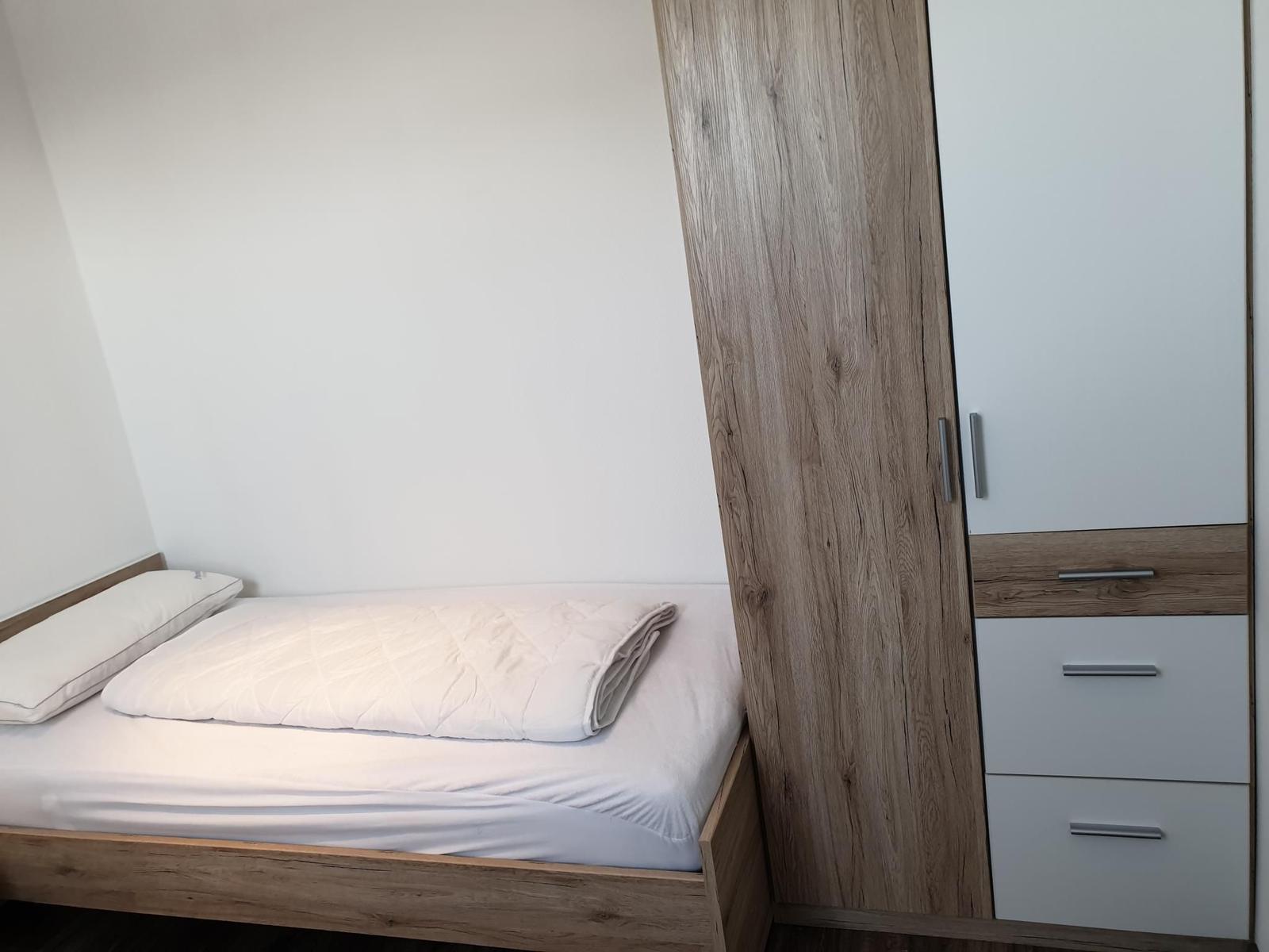 A bedroom with bed, pillow, and wardrobe.