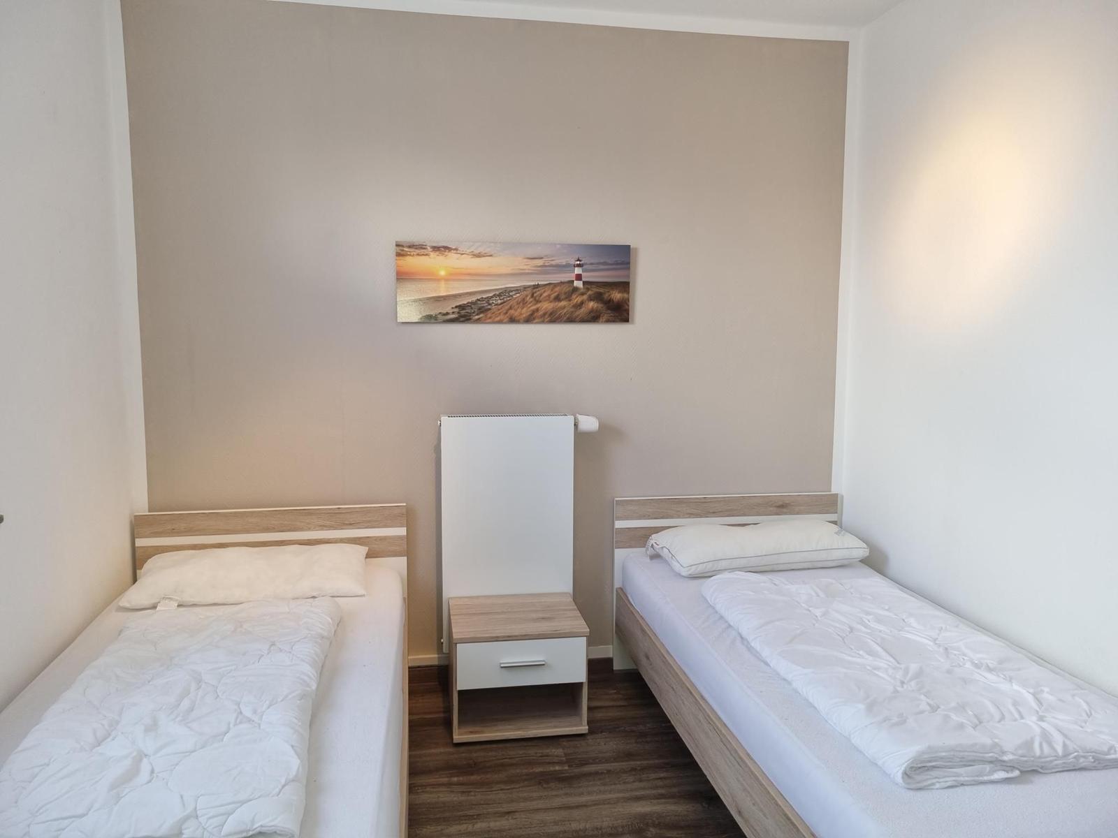 Two single beds with white bedding and nightstand