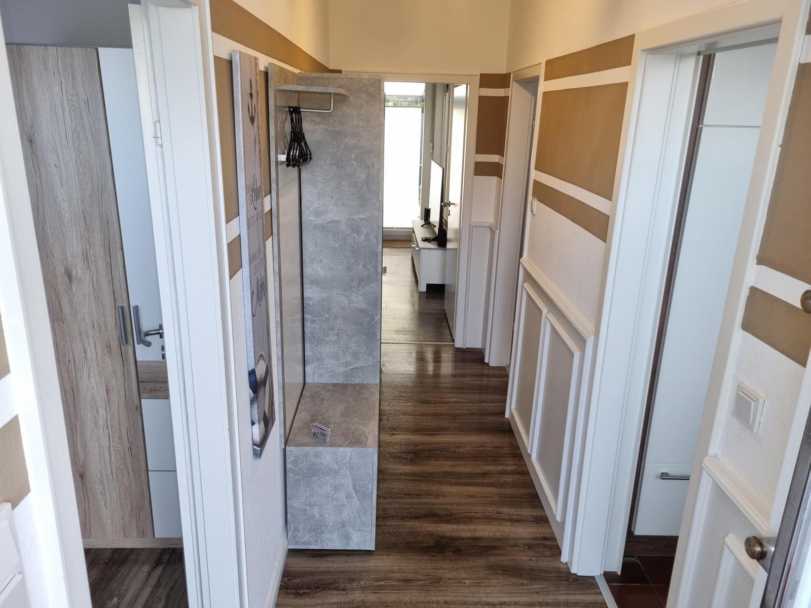 Hallway with wooden floor and wall paneling, door to bedroom and bathroom