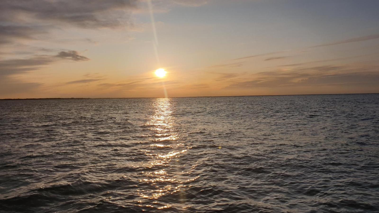 Sunset over the sea with reflection on the water surface.