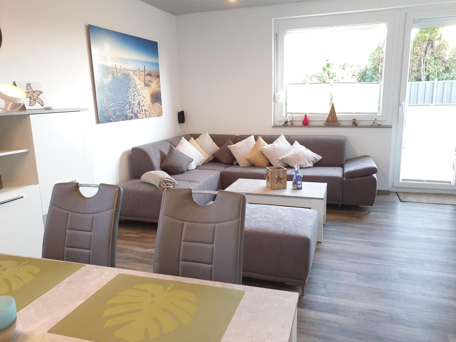 Living and dining area with sofa, table and chairs. Window and door to the terrace.