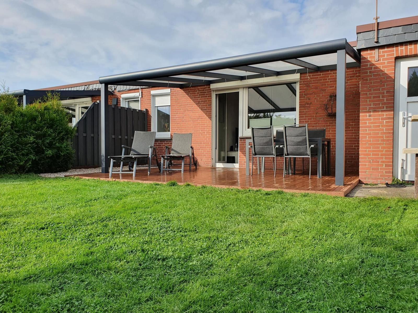 Terrace with seating and green lawn in front of a brick house.