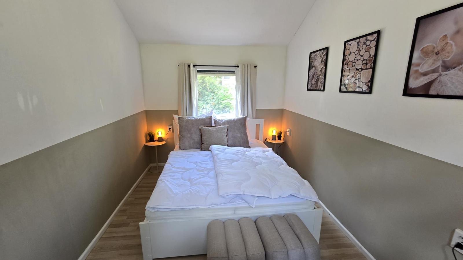 Schlafzimmer mit Bett, Fenster und Wandbildern