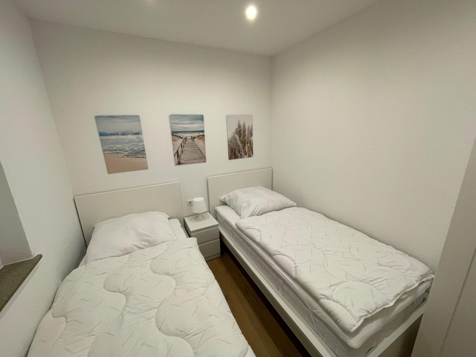 Zwei Einzelbetten mit weißen Bettwäschen und Wandbildern an der Wand.