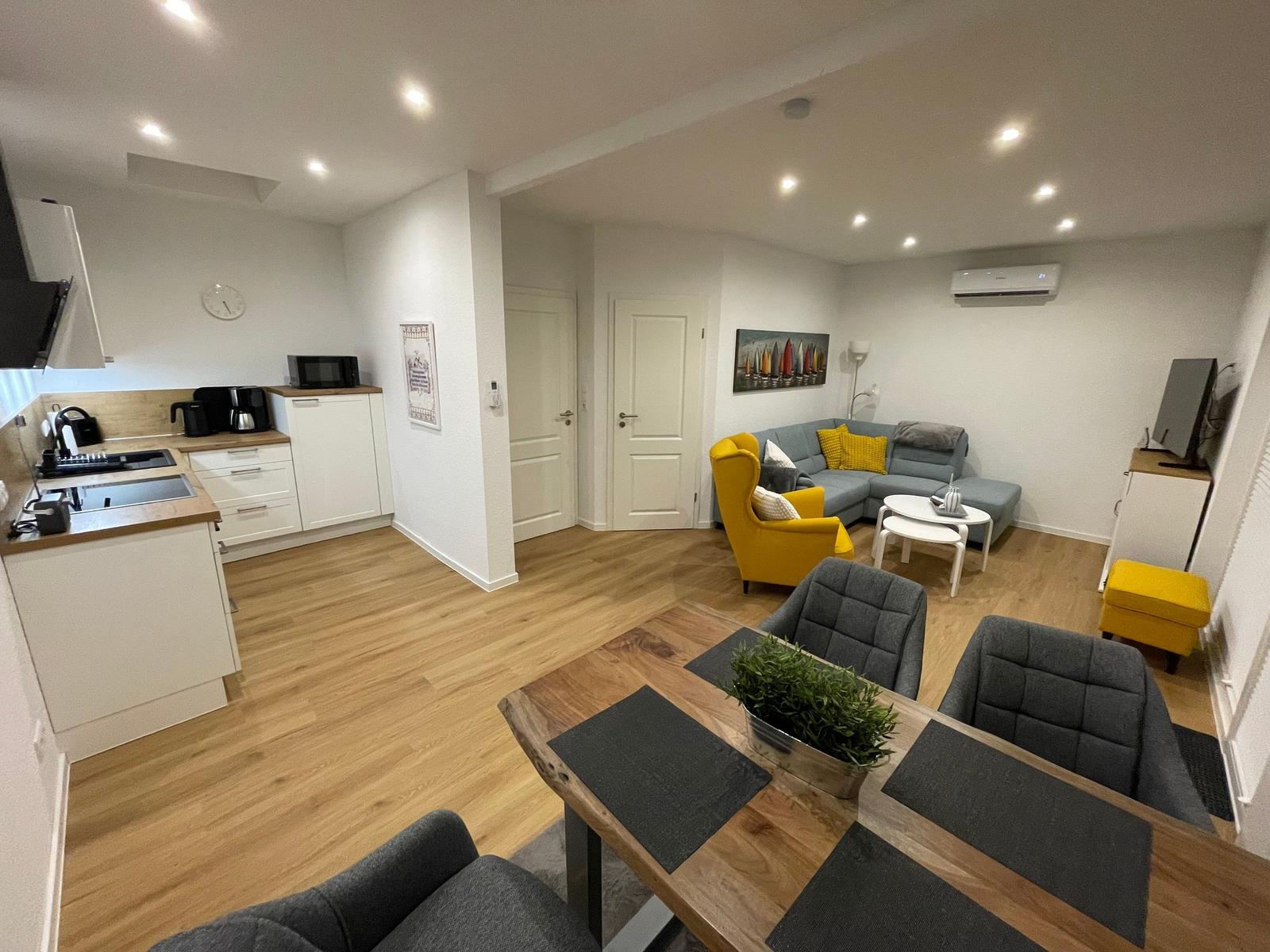 Wohnung mit Küche, Essbereich und Wohnzimmer mit Sofa und Stühlen.