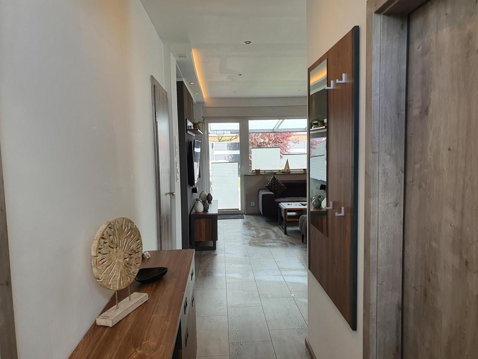 Hallenraum mit Holzmöbeln und Blick ins Wohnzimmer.