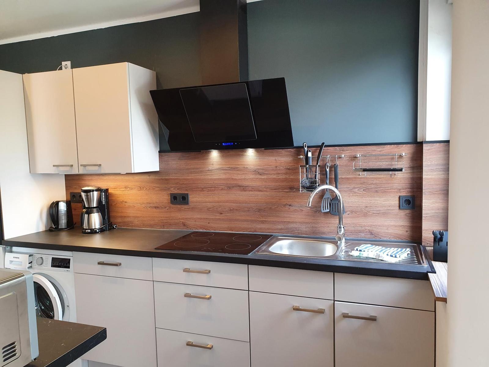 Moderne Küche mit Kochfeld, Spüle und Küchenzeile.